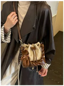 Lifestyle view of a cream canvas bucket bag with brown trim, braided handle and teddy bear charm