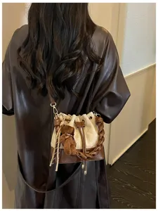 Back view of a woman carrying a brown and cream bucket bag with braided handle and teddy charm