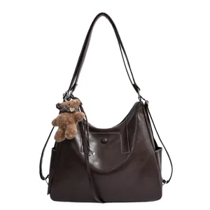 Brown faux leather shoulder tote with soft wavy texture, snap closure, and teddy bear charm