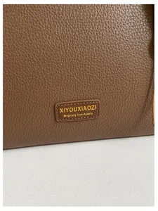Gros plan sur le similicuir brun grainé et l’étiquette cousue rectangulaire à lettrage doré