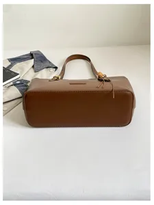 Vue du fond structuré du sac brun, avec coutures nettes et détails dorés près de l'anse