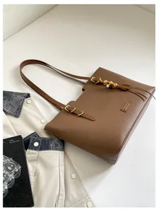 Vue en biais d’un sac en similicuir marron, avec fermoir doré, perles en bois et longues anses