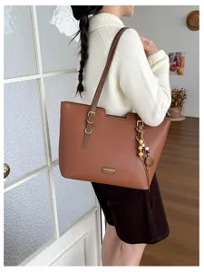 Sac marron porté par un modèle, texture grainée, détails dorés et breloques en perles de bois