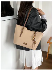 Vue portée du sac beige grainé, avec boucles dorées et breloque à pompon et perles en bois