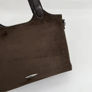 Detail van het bruine suèdeachtige oppervlak, de leren handgreep en het zilverkleurige metalen accent