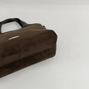 Detail van de bruine suèdelook, met de stevige dikke bodem en zichtbare naden van de tas