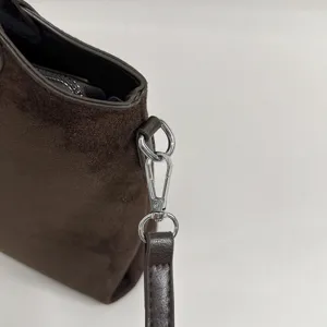 Close-up van bruine suède-look afwerking, zilveren haak en donkerbruine leren schouderriem