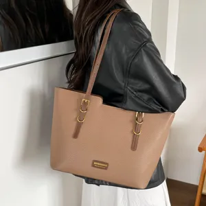 Cabas marron en similicuir grainé avec détails dorés, porté sur l’épaule par une femme