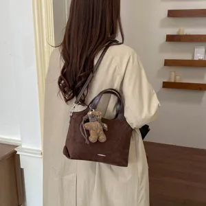 Bruine suède-look shopper met handvatten, schouderriem en teddybeertje als hanger, gedragen