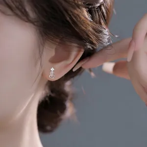 Gros plan sur une puce d’oreille argentée en forme de gourde, avec détail carré, portée à l’oreille