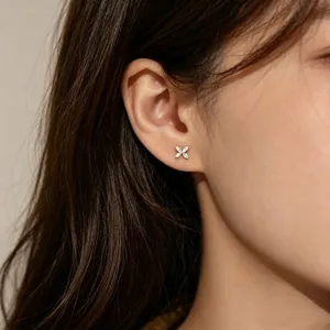 Gros plan sur une oreille portant une petite puce fleur à quatre pétales avec des pierres blanches