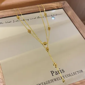 Close-up of a gold-tone layered necklace with oval openwork links and a delicate dangling tassel