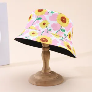 Detail of yellow sunflower and pink cloud print with black underside of a reversible hat visible.