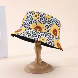Bucket hat displayed on a wooden stand, featuring bold sunflower and leopard print patterns