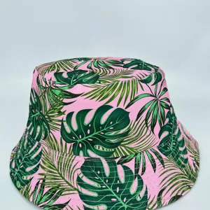 Front view highlighting the wide brim and bold green tropical leaf print on a pink fabric hat