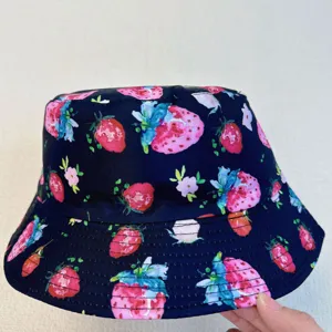 Angled view of a navy bucket hat with watercolor strawberries and flowers across its double brim