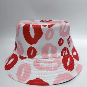 Front view of a white bucket hat covered in red and pink lip prints, with a stitched brim.