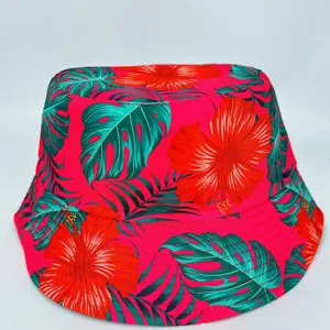 Detail of a red bucket hat with vibrant green tropical leaves and hibiscus flower print