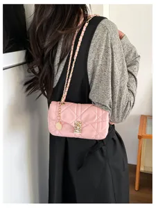 Borsa rosa trapuntata a catena indossata su un abito nero, con chiusura e ciondolo dorati