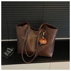 Braune Tasche aus mattem Kunstleder mit langen Henkeln, Flechtband und kleinem Bärenanhänger