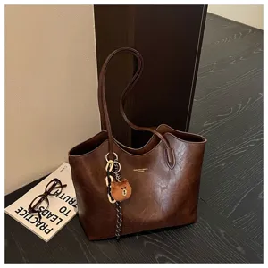 Braune Kunstleder-Tasche mit gewachster Struktur, langen Henkeln und Plüschbären-Anhänger