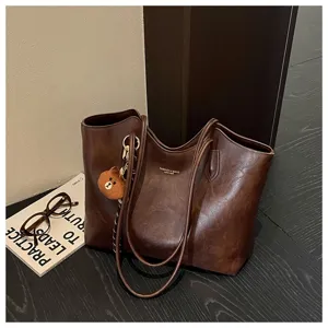Braune Kunstledertasche mit Vintage-Wachsoptik, langen Henkeln und kleinem Bärenanhänger