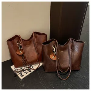 Zwei braune Kunstledertaschen nebeneinander, mit langen Riemen und kleinen Bärenanhängern