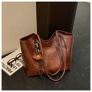 Braune Tasche mit wachsartiger Optik, langen Riemen, Flechtkordel und kleinem Bärenanhänger