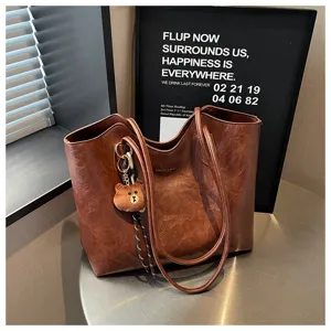 Braune Kunstledertasche mit gewachster Vintage-Optik, runden Henkeln und Teddybär-Anhänger