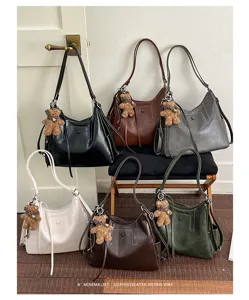 Six faux-leather handbags in assorted colors, displayed on a bench with teddy bear charms
