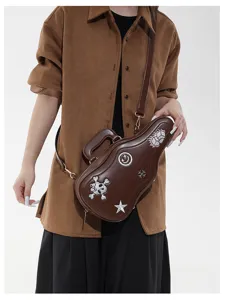 Sac brun en forme de guitare porté en bandoulière, avec motifs brodés et sangle réglable