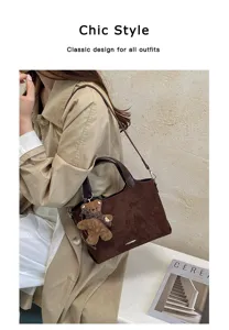 Model carrying a deep brown suede-look tote with a plush bear charm over a beige trench coat