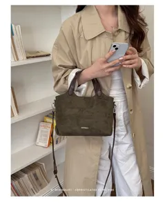 Olive faux-suede bag with dark brown handles and a detachable strap, styled with a beige coat