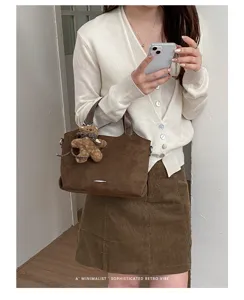Brown textured bag with silver-tone trim and plush bear charm, styled with a casual outfit