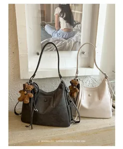 Two retro PU leather shoulder bags in charcoal and cream, each with a teddy bear charm