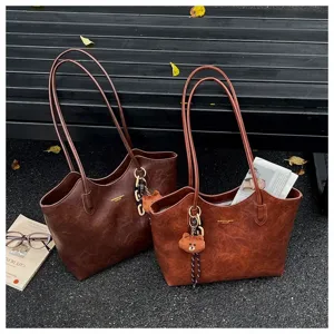 Zwei braune Kunstledertaschen mit langen Schulterriemen, Bärenanhängern und Kettendetails