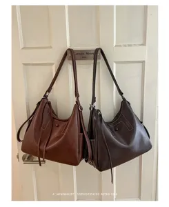 Two brown faux-leather shoulder bags with adjustable straps hang side by side on a paneled door