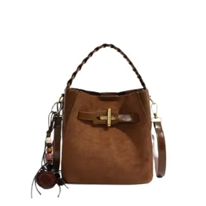 Brown faux suede bucket bag with braided handle, gold-tone clasp, and detachable shoulder strap