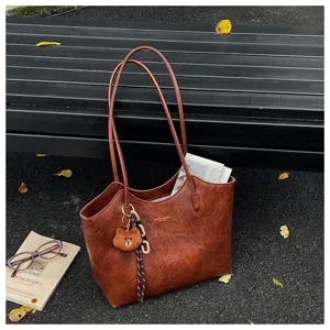 Braune Tasche mit geprägter Optik, langen Henkeln, goldfarbenen Beschlägen und Bärenanhänger