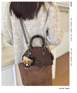 Vue de dos d’un modèle portant un sac brun à texture suédée, orné d’un petit porte-clés en peluche