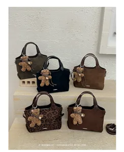 Suede-textured handbags in brown, black and leopard print, displayed with plush bear charms