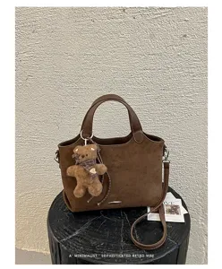 Brown suede-textured tote displayed with a teddy bear charm and detachable shoulder strap