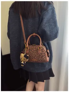 Sac à imprimé léopard porté avec une tenue en maille, poignées brunes et pendentif chat tout doux