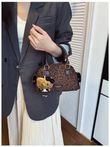 Détail d’un sac à main marron à imprimé léopard, anses effet cuir et petit pendentif en peluche