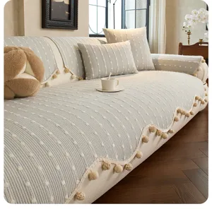 Living room view of a cream sofa cover with raised gray stripes and pom-pom trim along the edge