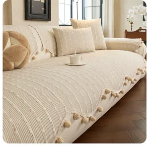 Cream sofa cover with raised knit texture and pom-pom fringe, styled with matching cushions