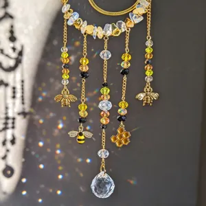 Close-up of dangling bee and honeycomb charms with crystal beads scattering colorful sunlight