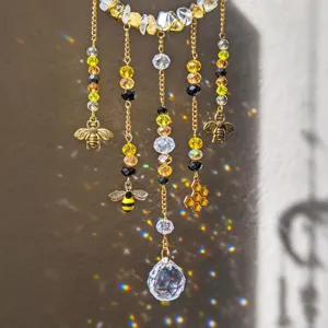 Close-up of gold chains, bee and honeycomb charms, colorful beads and a crystal catching sunlight