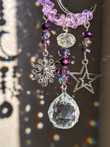 Primo piano di perline viola, ciondoli argentati a forma di sole e stella e cristallo sfaccettato