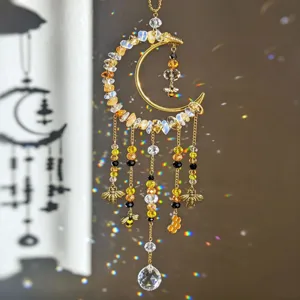 Golden crescent moon bee and honeycomb crystal suncatcher hanging by a window, casting rainbow light